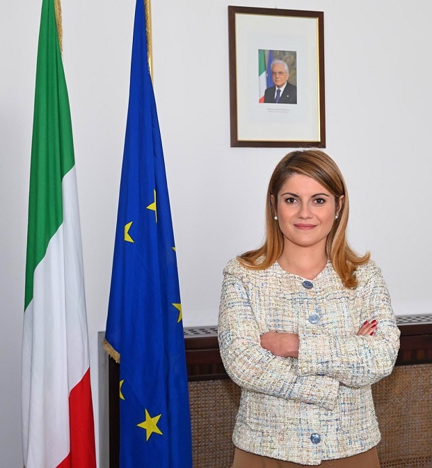 Il Sottosegretario agli Affari Esteri Maria Tripodi in un ufficio istituzionale con le bandiere italiana ed europea.