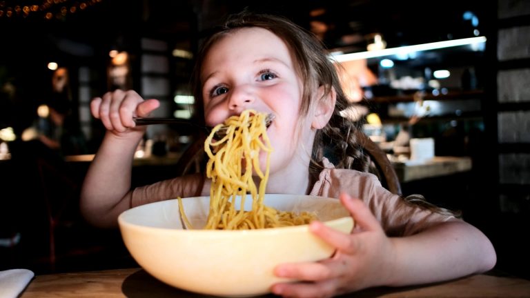 Frame di una bambina che si gode un piatto di pasta nella giornata della pasta