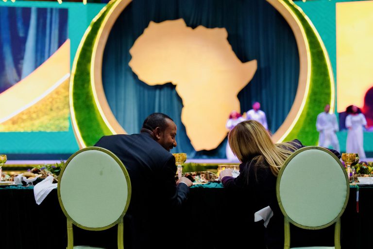 Evento dedicato alla cooperazione tra Italia e Africa nell’ambito del Piano Mattei, con rappresentazione del continente africano sullo sfondo.